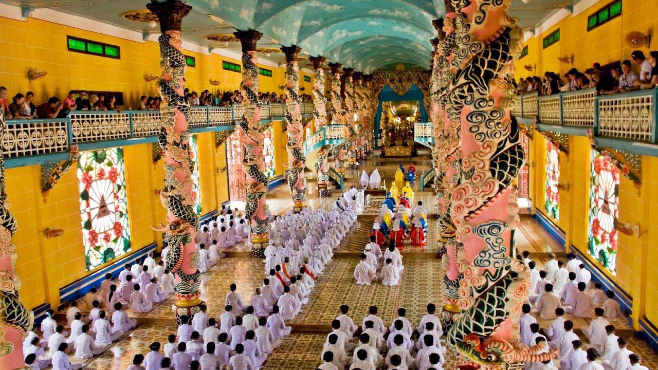 Colorful interior and worshippers at the Cao Dai temple in Tay Ninh, Vietnam