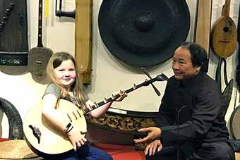 Young girl learning to play Vietnamese traditional instrument in Hanoi